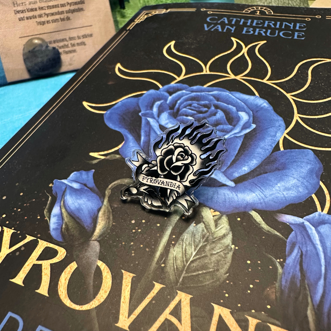 Das Bild zeigt eine Detail-Aufnahme des Akryl-Pins mit dem Motiv "Pyrovandische Rose" (Brennende Rose im Tattoo-Design mit Banderole und der Aufschrift "Pyrovandia").